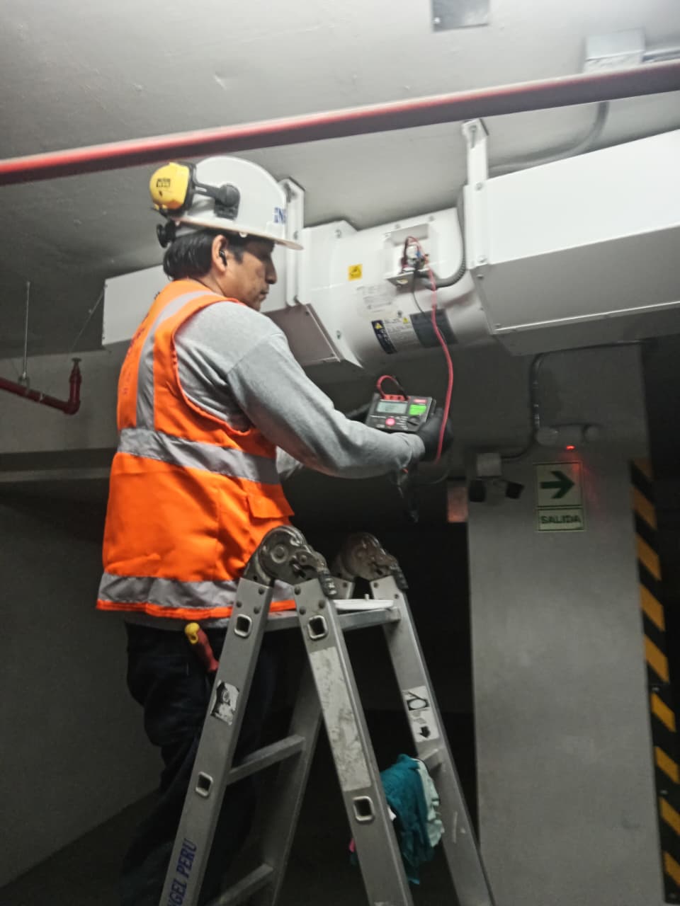 Técnicos realizando mantenimiento e instalación de sistema de extracción de monóxido de carbono en estacionamiento